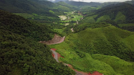 Logistic-concept-aerial-view-of-countryside-road---motorway-passing-through-the-serene-lush-greenery-and-foliage-tropical-rain-forest-mountain-landscape