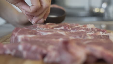 Close-shot-of-fingers-putting-salt-on-raw-meat-in-the-kitchen