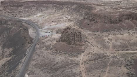 Dusty-trails-crisscross-a-weathered-stone-spire-Frenchman's-Coulee,-Aerial-orbit