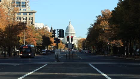 Cars-and-bus-driving-on-road,traffic-avenue-with-the-us-capitol-building-in-background-during-sunny-autumn-day