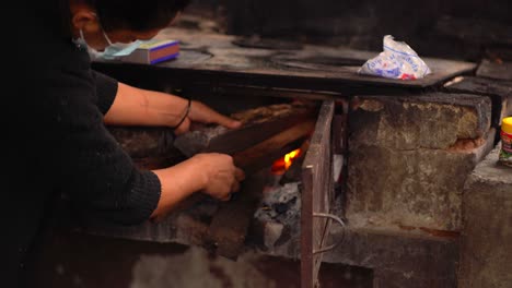 Woman-lighting-log-stove.-Woman-in-rural-kitchen
