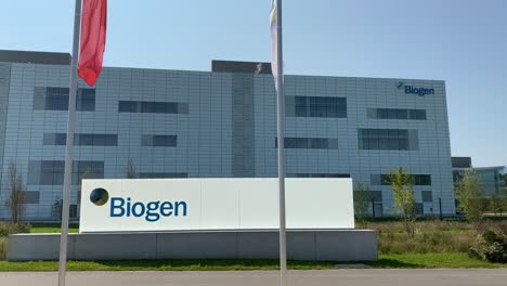 Wide-shot-of-Biogen-company-building-with-sign-mark-and-waving-flags