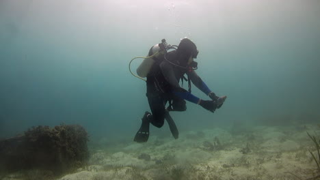 Scuba-diver-picking-up-plastic-bottle-from-ocean-floor