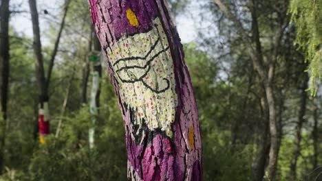 Close-up-shot-of-colorful-painted-wooden-tree-in-forest-during-sunny-day-in-nature