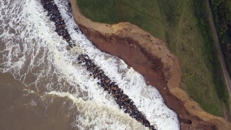 Aerial-drone-footage-top-down-on-high-tide-as-the-sea-crashes-into-sea-defences