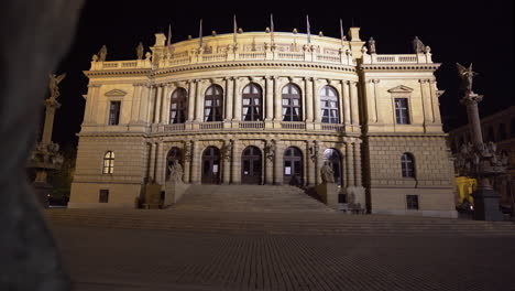 The-maginificent-concert-hall-of-Rudolfinum-with-bright-facade-in-Prague,-Czechia-on-an-empty-square-of-paved-stones-at-night,-during-a-Covid-19-lockdown-and-no-people-anywhere,-zooming-shot