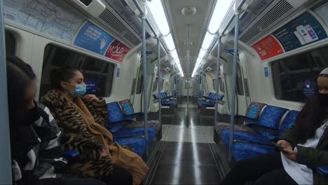 Drei-Frauen-Sitzen-Im-Zug-Der-Jubiläumslinie-Und-Tragen-Gesichtsmasken-Und-Soziale-Distanzierung