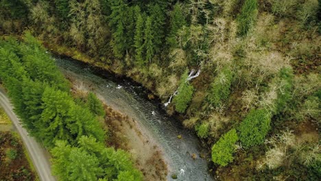 Picturesque-cascading-waterfall-joins-larger-stream,-Descending-circling-aerial-shot