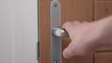 A-close-up-shot-of-a-mans-hand-closing-a-door,-focusing-on-the-handle