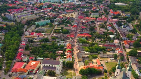 Top-aerial-panoramic-view-of-Lowicz-old-town-historical-city-centre-with-Rynek-Market-Square,-Old-Town-Hall,-New-City-Hall,-colorful-buildings-with-multicolored-facade-and-tiled-roofs,-Poland
