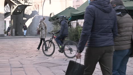 Menschen-Mit-Maske-Gehen-An-Einem-Wintermorgen-In-Monza,-Norditalien,-Durch-Die-Straßen-Der-Stadt,-Restaurantbar-Mit-Außenpflanzen-Im-Hintergrund---Statische-Aufnahme