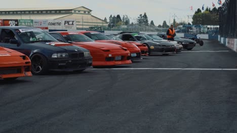 Different-Models-of-Nissan-Drift-Cars-Lined-Up-on-Racing-Track,-Wide-View