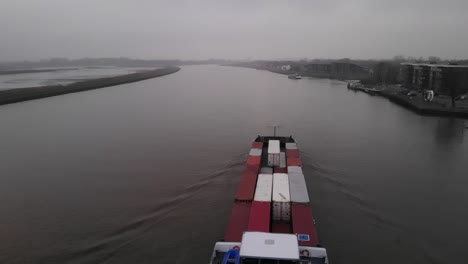 Barcaza-De-Contenedores-Navegando-En-Un-Río-Holandés-Cerca-De-Rotterdam-Mientras-Un-Ferry-De-Pasajeros-Navega-En-La-Otra-Dirección-En-El-Lado-Equivocado-Del-Río-En-Un-Día-Brumoso