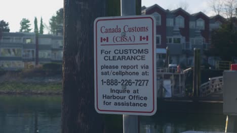 A-Canada-Customs-Sign-indicating-a-phone-number-to-call-for-customs-and-clearance-at-Fisherman's-Wharf-at-Vancouver-Island