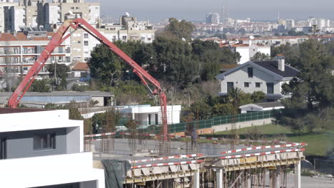Static-wide-shot-showing-construction-site-with-crane-and-workers-on-the-rooftop-of-a-new-modern-building