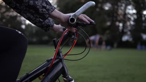 Female-hands-on-bicycle-in-the-park-medium-shot-slow-tilting-shot