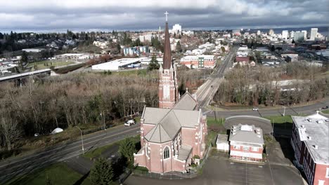 Sun-shines-on-the-Holy-Rosary-Catholic-Church,-storm-clouds-in-the-background,-aerial-orbit