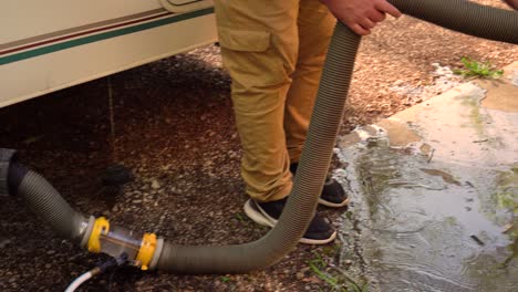 A-man-fixes-the-water-hose-to-flush-out-waste-on-an-RV