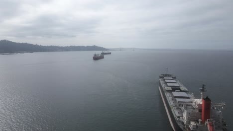 Three-ocean-going-container-ships-anchored-near-the-mouth-of-the-Columbia-River,-aerial