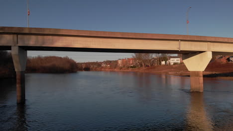 Passing-underneath-bridge-above-surface-of-Susquehanna-river,-Aerial