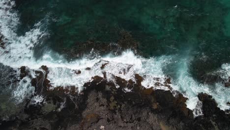 Steady-view-of-waves-crashing-against-lava-rocks
