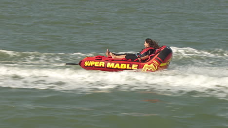kids-on-a-towable-tube-behind-a-motorboat-at-sea-in-summertime-having-fun