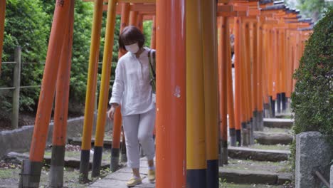Menschen,-Die-Während-Der-Koronakrise-Eine-Gesichtsmaske-Tragen,-Passieren-Typische-Japanische-Rote-Torii-tore
