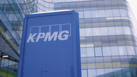 Slow-pan-of-KPMG-sign-in-front-of-large-office-building,-snow-falls