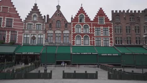 A-mother,-child-walk-across-a-deserted-Bruges-Market-square,-mandated-closure,-Coronavirus-pandemic