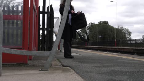 Business-woman-looking-in-briefcase-at-railway-station-wide-shot
