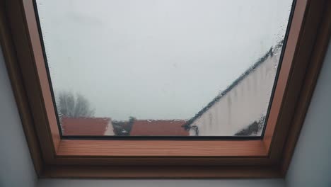 Rain-falling-on-a-loft-slanted-bay-window-on-an-overcast-day-in-England