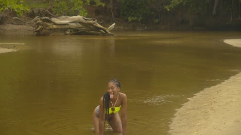 Muscular-bikini-model-bending-over-in-the-river-while-posing-for-the-camera