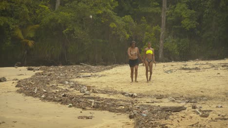 Zwei-Mädchen-Gehen-Den-Fluss-Hinunter,-Der-Im-Hintergrund-In-Den-Ozean-Mündet