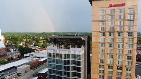 Aerial-pan-of-rooftop-bar-at-Marriott-Hotel-and-Convention-Center-in-Lancaster-Pennsylvania,-rainbow-on-horizon