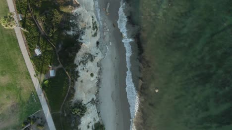Birdseye-view-of-a-public-park-on-the-shoreline-of-the-Pacific-ocean-during-sunset