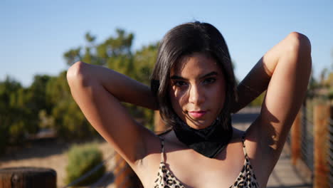 A-beautiful-young-hispanic-woman-fashion-model-tying-a-bandana-and-staring-in-an-outdoor-desert-landscape-SLOW-MOTION