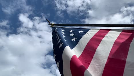 a-billowing-American-flag-under-a-sunny,-cloudy-sky