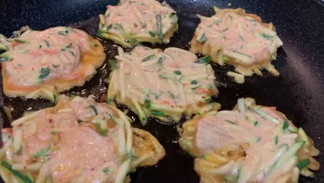Korean-kimchi-veggie-pancakes-frying-on-a-large-skillet-with-oil-bubbling-underneath