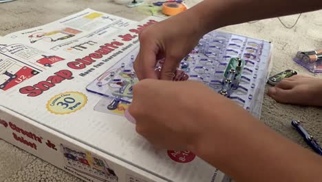 A-time-lapse-video-of-small-hands-busily-putting-together-snap-circuits-on-the-plastic-board-to-create-sound-and-light