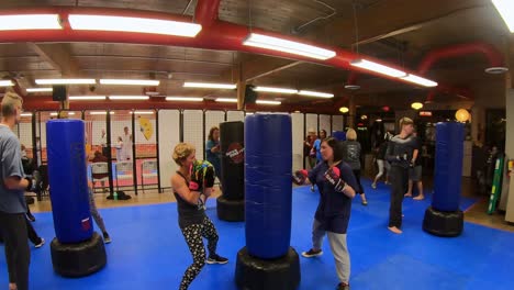 Adult-students-practicing-backhand-strikes-and-punches-while-participating-in-a-self-defense-class-at-martial-arts-school