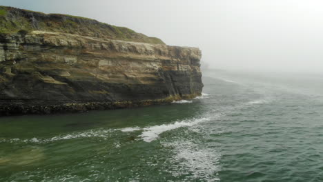Aerial-Fly-Over-Cliffside-on-Foggy-Ocean