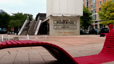Bright-red-modern-seating-near-fountains-in-a-plaza-outside-of-restaurants-in-the-Navy-Yard-area-of-Washington,-DC