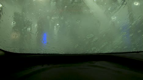automatic-carwash-water-spray-on-foamy-windshield-4k-pov