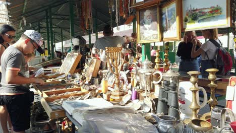 People-shopping-antiques-and-used-goods-at-flea-market-in-Krakow,-Pan-slow-motion