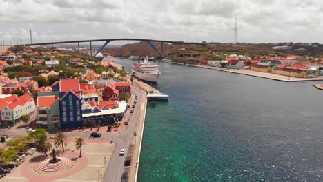 Un-Puente-Que-Cruza-La-Bahía-De-Sint-Anna-Con-Dos-Cruceros-Atracados-En-El-Puerto