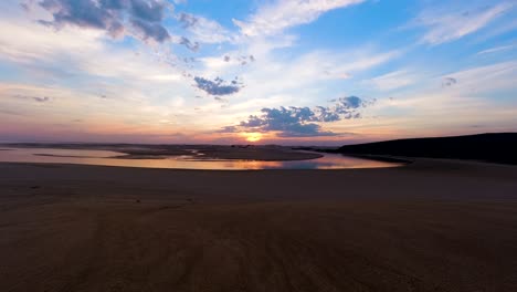 Time-lapse-of-sunset-reflection-over-river-mouth-and-sand-dunes,-Africa
