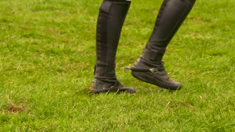 Person-in-riding-boots-walking-through-the-grass-at-an-equestrian-competition
