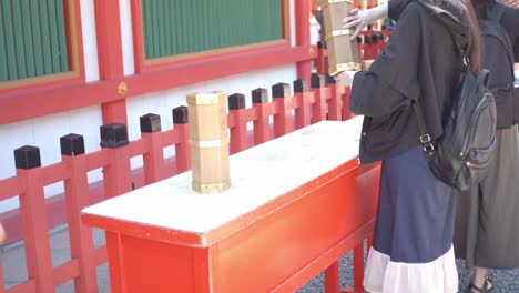 Mädchen,-Das-Eine-Glücksbox-In-Kyoto,-Japan,-Schüttelt,-Sanfte-Beleuchtung,-Zeitlupe-4k