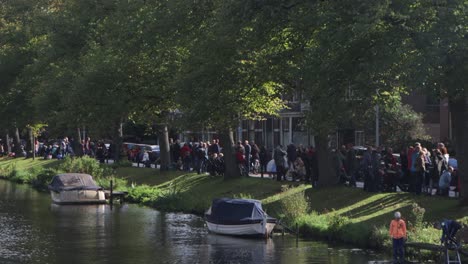 People-lining-the-streets-of-a-canal-in-Leiden,-the-Netherlands,-on-the-annual-October-celebration-of-the-Relief-of-Leiden