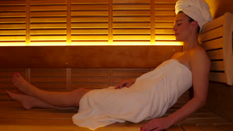 Attractive-adult-caucasian-woman-laying-in-modern-Finnish-sauna